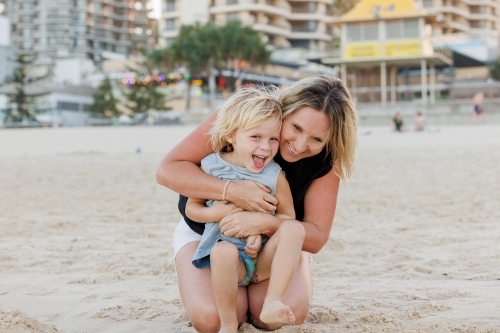 Mother embracing son on Main Beach at Surfers Paradise on the Gold Coast - Australian Stock Image