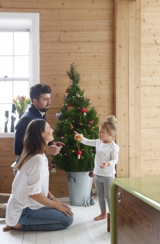 Mother, father and daughter in front of Christmas tree