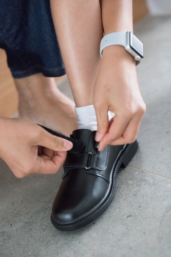 Mother helps her son put on his new school shoes for his first day of school - Australian Stock Image