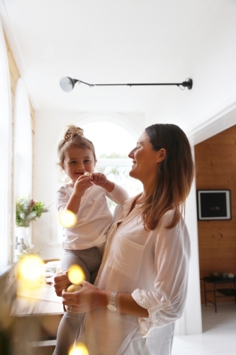 Mother holding daughter in front of Christmas lights - Australian Stock Image