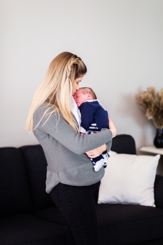 Mother holding newborn baby boy in arms cuddling - Australian Stock Image