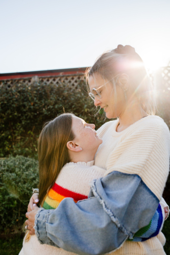 Mother hugging preteen daughter in the garden - Australian Stock Image