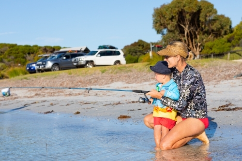 Mother kneeling to help her son fishing - Australian Stock Image
