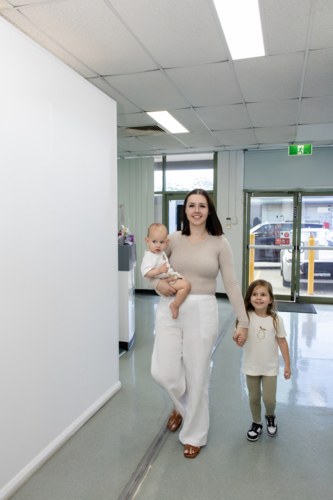 Mother of two walking along the hallway of the healthcare facility - Australian Stock Image
