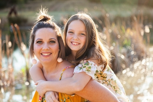 Mother piggybacking daughter in park