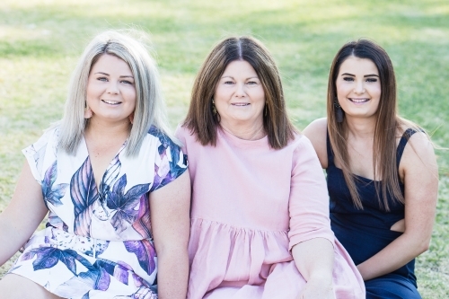 Mother sitting between two daughters smiling - Australian Stock Image
