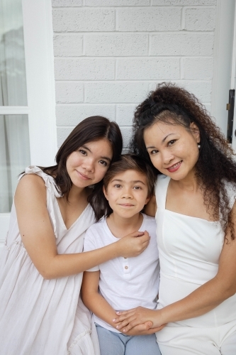 Mother, son and daughter wearing white sitting together - Australian Stock Image
