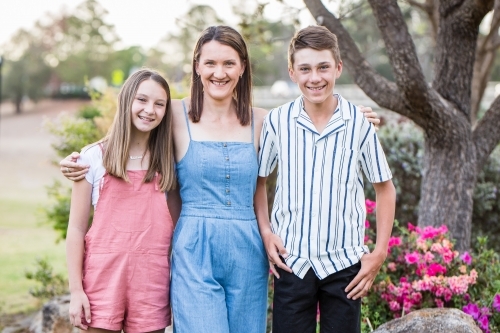 Mother standing with her arms around her son and daughter - Australian Stock Image