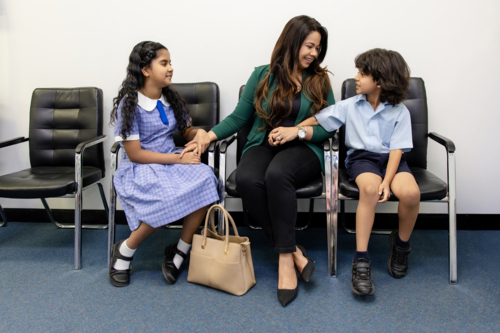 Mother with her two kids seated on waiting area of doctors clinic - Australian Stock Image
