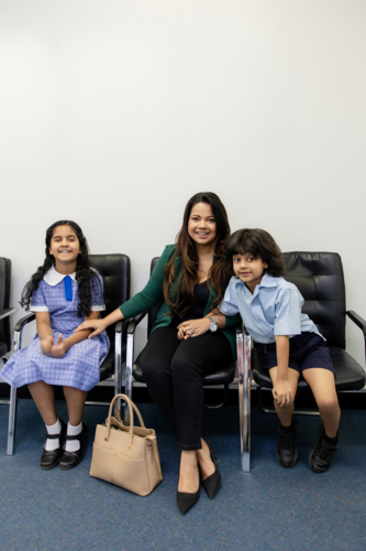 Mother with her two kids seated on waiting area of doctors clinic - Australian Stock Image