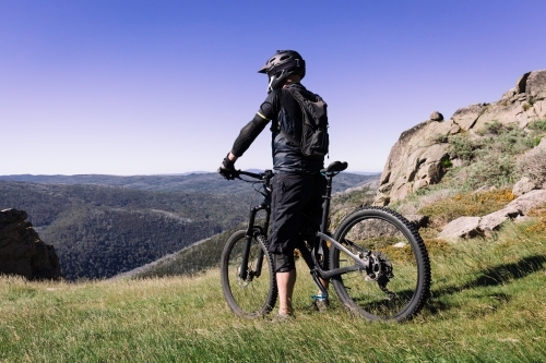 Mountain biker contemplating riding down Mount Kosciuscko - Australian Stock Image