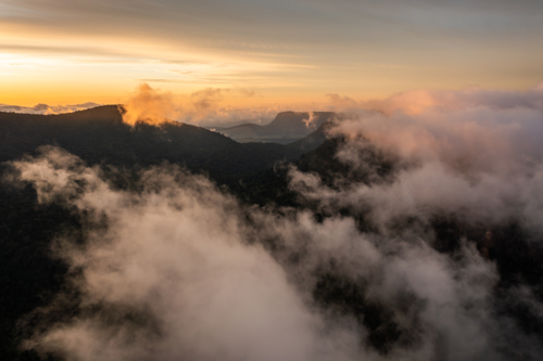 mountain landscape with morning golden light above low clouds - Australian Stock Image