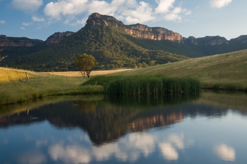Mountain, paddock and sky reflected in farm dam water - Australian Stock Image