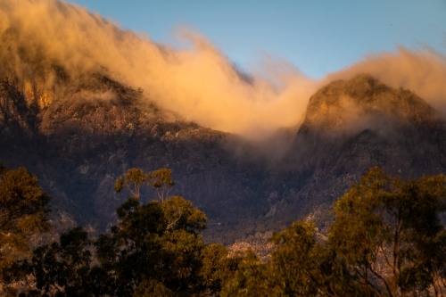 Mountain range with low-hanging clouds enveloping the peaks. - Australian Stock Image