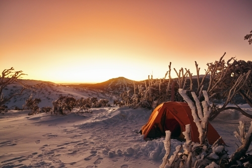 Mountain vista snow camping overlooking a sunrise at dawn with fresh snow and ice - Australian Stock Image