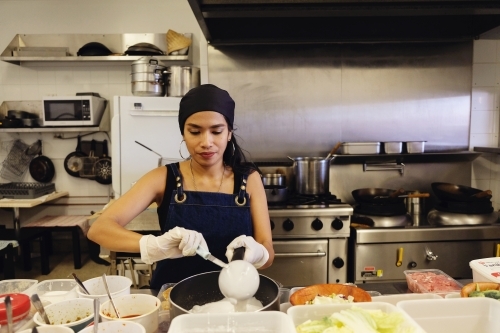 Multicultural Asian chef cooking in Thai small business restaurant - Australian Stock Image