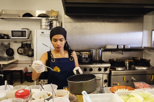 Multicultural Asian chef cooking in Thai small business restaurant - Australian Stock Image