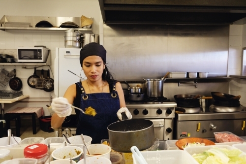 Multicultural Asian chef cooking in Thai small business restaurant