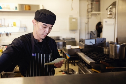 Multicultural Asian chef in Thai small business restaurant - Australian Stock Image