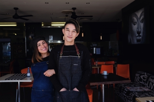 Multicultural Asian small business owners greeting in front of Thai restaurant - Australian Stock Image