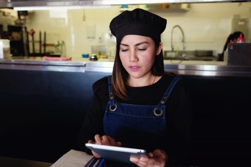 Multicultural Asian waitress taking order at Thai restaurant - Australian Stock Image