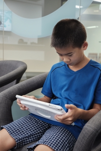 multicultural preteen boy using digital tablet - Australian Stock Image
