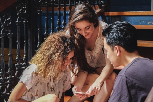 Multicultural teenagers hanging out and using mobile phone - Australian Stock Image