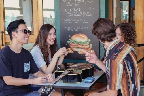 Multicultural teenagers hanging out at cafe - Australian Stock Image