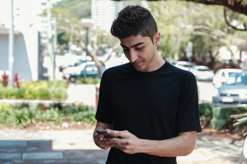 multicultural young adult man using smartphone - Australian Stock Image