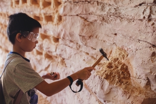 Multiethnic young boy chipping away at the mine wall,  having Opal mining experience - Australian Stock Image
