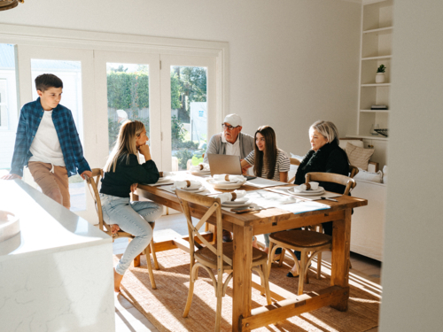 Multigeneration family gathered in the dining table while working on the computer. - Australian Stock Image