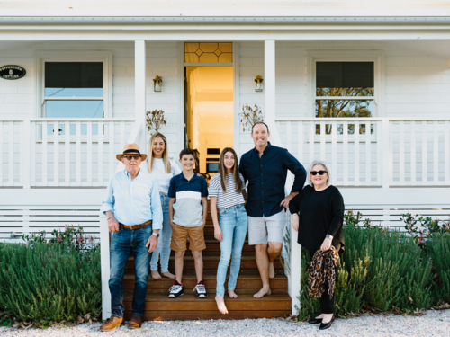 Multigeneration family standing on a wooden step of their porch. - Australian Stock Image