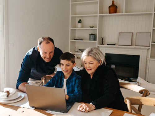 Multigeneration family working in front of a computer. - Australian Stock Image