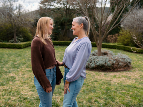 Mum and teenage daughter stands closely in the backyard looking at each other - Australian Stock Image