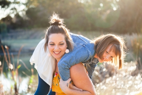 Mum carrying 8yo daughter over her shoulder laughing together - Australian Stock Image