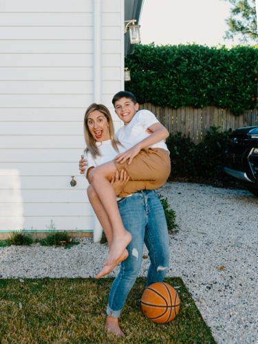 Mum carrying her son outside the front yard of the house. - Australian Stock Image