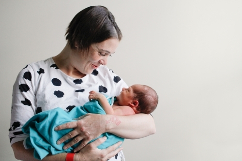 Mum holding and smiling at newborn baby - Australian Stock Image