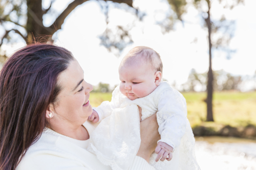 Mum holding newborn baby girl smiling outside - Australian Stock Image