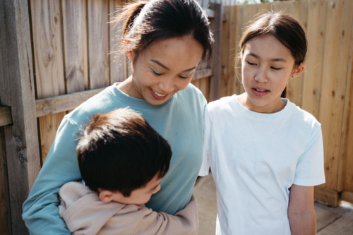 Mum hugging her children outside their house. - Australian Stock Image