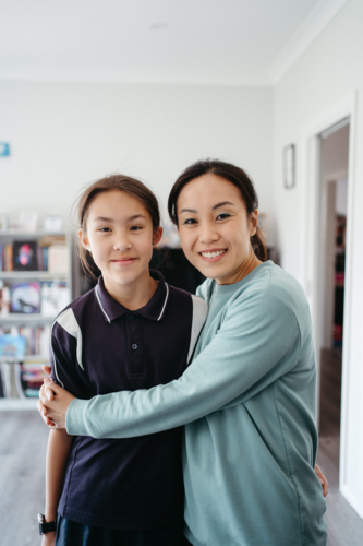 Mum hugging her daughter inside their home. - Australian Stock Image