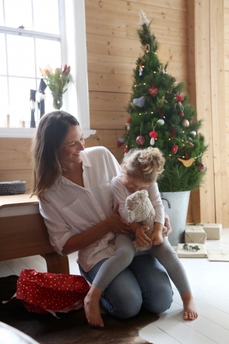 Mum laughing with daughter in front of Christmas tree