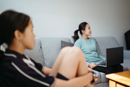 Mum sitting on the couch with her laptop. - Australian Stock Image