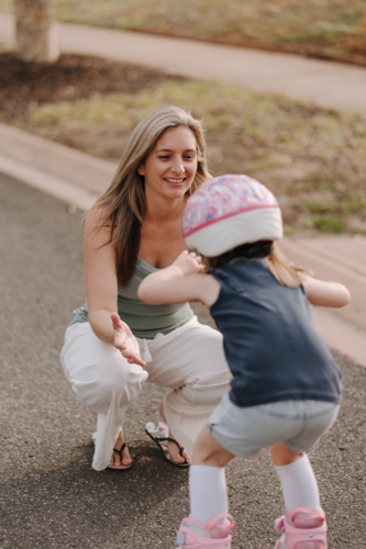 Mum with daughter on roller blades on the street. - Australian Stock Image