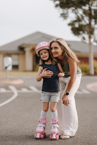 Mum with daughter on roller blades on the street. - Australian Stock Image