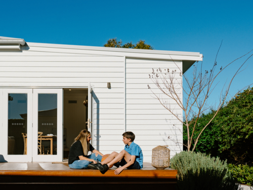 Mum with her son sitting outside in the wooden deck. - Australian Stock Image