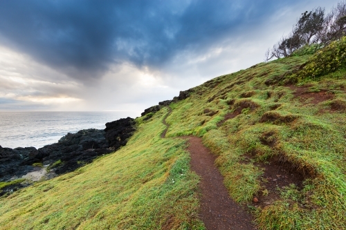 Narrow walking track on a grassy headland on an overcast day