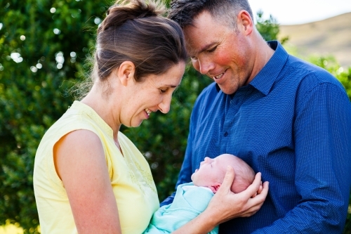 New mum and dad with baby smiling together outside on farm - Australian Stock Image