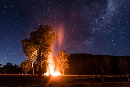 Night scene with a bonfire under some trees and the Milky Way - Australian Stock Image