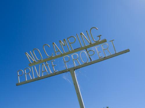 No Camping, Private Property metal sign against a blue sky