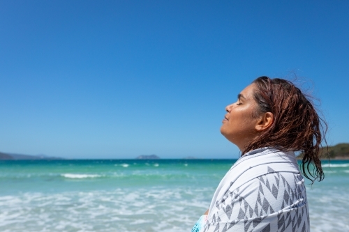 noongar woman enjoying sunshine on her face after swimming - Australian Stock Image